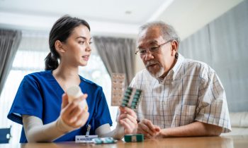 Asian Senior elderly male patient consult with physician nurse at nursing home care. Caregiver therapist pharmacist girl hold medicine pills bottle, explain prescription to older disabled guy in house Asian Senior elderly male patient consult with physician nurse at nursing home care. Caregiver therapist pharmacist girl hold medicine pills bottle, explain prescription to older disabled guy in house