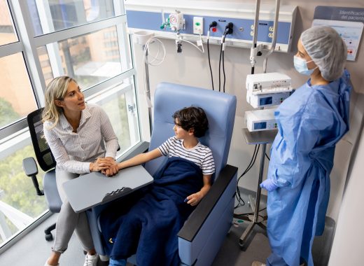 Latin American boy at the hospital holding hands with his mother while getting his chemotherapy treatment and talking to the nurse