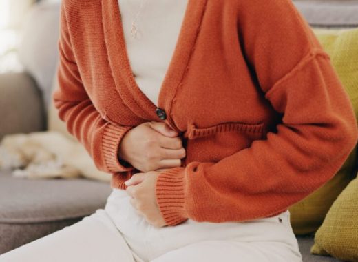 Stomach ache, cramps and hands of woman with abdomen pain due to constipation, menstruation or ibs issue. Sick, home and person suffering and holding belly in a house lounge, couch and living room